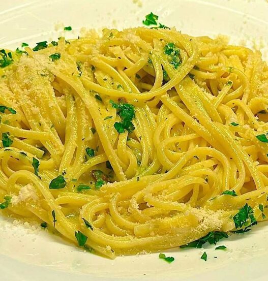 spaghetti con prezzemolo e formaggio su piatto bianco